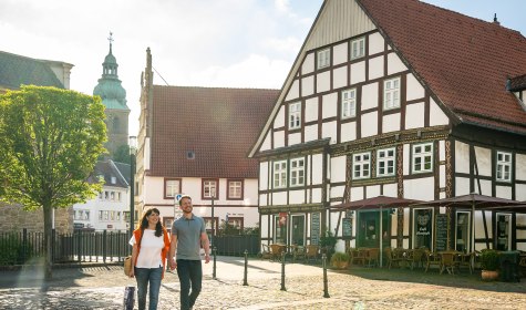 Ein Paar spaziert &uuml;ber den Salzhof in Bad Salzuflenm Fachwerkh&auml;user und Stadtkirche im Hintergrund