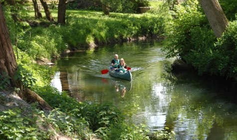 2 Personen paddeln im Kanadier auf einem Fluss