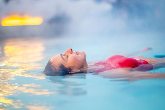Frau liegt schwebend auf der Wasseroberfläche in einem Außenbecken der Vitasol-Therme
