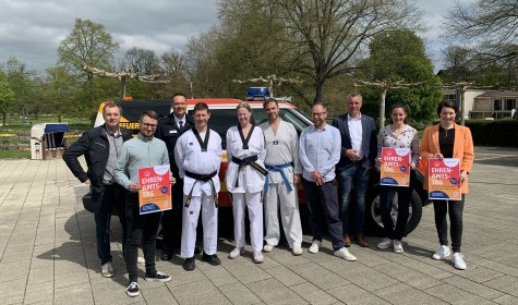 Mehrere Personen stehen im Kurpark vor einem Fahrzeug der Freiwilligen Feuerwehr und schauen in die Kamera, es handelt sich um Perosnen aus der Stadtverwaltung, von der Feuerwehr und von dem Verein Taekwando e.V. Koryo, © Stadt Bad Salzuflen