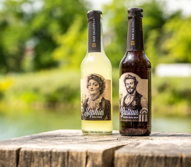 Stadt-Bad-Salzuflen-Teutoburger-Wald-D.-Ketz-085 2 Getränkeflaschen stehen auf einem Holzsteg im Kurpark: Eine 0,33l Flasche Gustavs Helles Sole-Bier und eine Flasche Sophies Sole-Limo