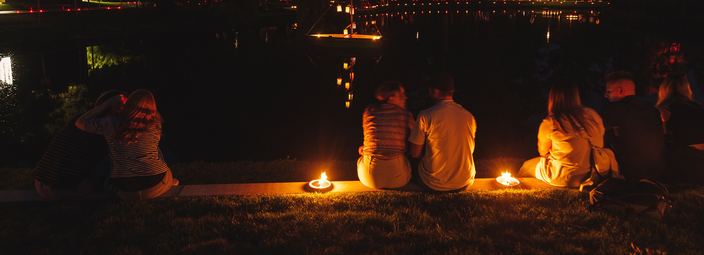 2 Personen sitzen bei Kerzenschein am kleinen Kurparksee bei der Veranstaltung "Nacht der 10.000 Kerzen""