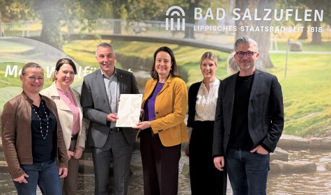 Neuer Meilenstein f&uuml;r die touristische Weiterentwicklung in Bad Salzuflen: Regierungspr&auml;sidentin Anna Katharina B&ouml;lling (3.v.r.) &uuml;bergab den F&ouml;rderbescheid f&uuml;r das Zukunftsprojekt &bdquo;Erlebniswelt Kneipp&ldquo; im Landschaftsgarten an B&uuml;rgermeister Dirk Tolkemitt (3.v.l.), Melanie Koring (2.v.r., Erste Beigeordnete & Stadtk&auml;mmerin), Ulrike Niebuhr (links, Technische Beigeordnete), Ralf Hammacher (rechts, Fachbereichsleitung Tourismus, Gesundheit, Kultur) und Katja M&ouml;nnigmann-Steinbeck (2.v.l., Fachbereichsleitung Jugend, Soziale Dienste, Schule). , &copy; Stadt Bad Salzuflen