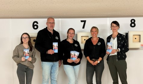 Sportlich aktiv mit &bdquo;Sporteln & Familienspa&szlig;&ldquo; auch 2026/2027: Als eines von acht Freizeittipps l&auml;dt die Sch&uuml;tzengesellschaft Sch&ouml;tmar von 1732 e.V. dazu ein, das Sportschie&szlig;en an einer RedDot-Anlage mit Lasergewehr zu testen. Ausprobiert haben dies (von links) Lenya Tomak (Stab Ehrenamt & Sport, Stadt Bad Salzuflen), die Sch&uuml;tzengesellschaftsmitglieder Christian Hellmich, Bettina Hellmich und Janina Balk sowie Sybille L&uuml;decke (Koordinatorin &bdquo;Lokales B&uuml;ndnis f&uuml;r Familien&ldquo;, Stadt Bad Salzuflen)., &copy; Stadt Bad Salzuflen