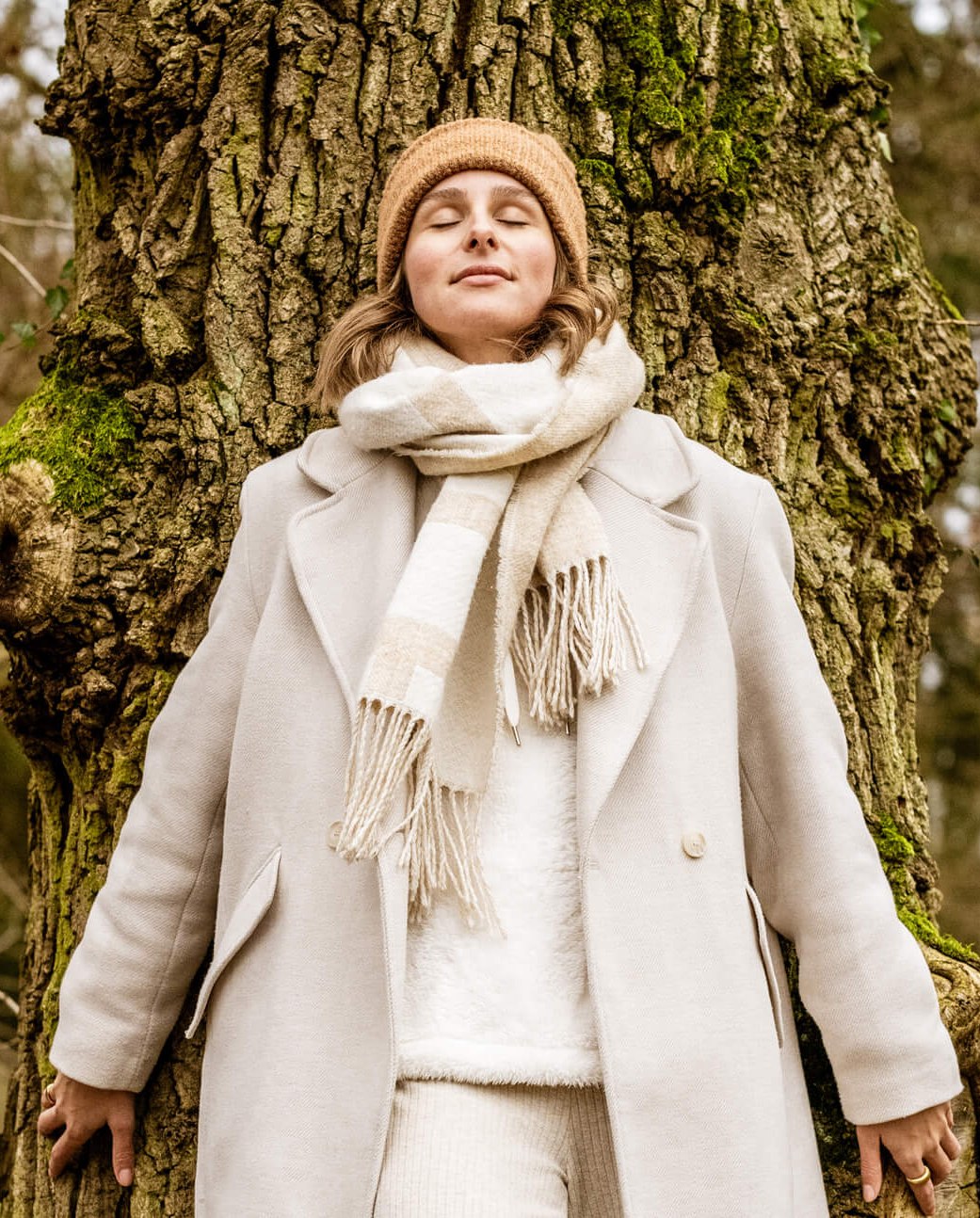 Frau genießt die Natur im Bad Salzufler Landschaftsgarten, © ©Stadt Bad Salzuflen_Teutoburger Wald_D. Ketz Eine hell gekleidete Frau lehnt an einer alten Eiche im herbstlichen Bad Salzufler Landschaftsgarten. Sie hat die Augen geschlossen und wirkt entspannt.