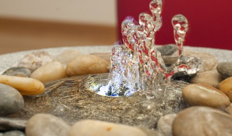 Besondere Wohlfühlatmosphäre: Das Plätschern des Wassers ist belebend und beruhigend zugleich. Ein Brunnen erinnert an sprudelnde Quellen im Wald oder plätschernde Bergbächlein. Sie verbessern die Raumluft, erhöhen die Luftfeuchtigkeit und das Plätschern des Wassers wirkt sich positiv auf unser Wohlbefinden aus., © IN-TI Institut für Tinnitus Diagnostik und Therapie GmbH